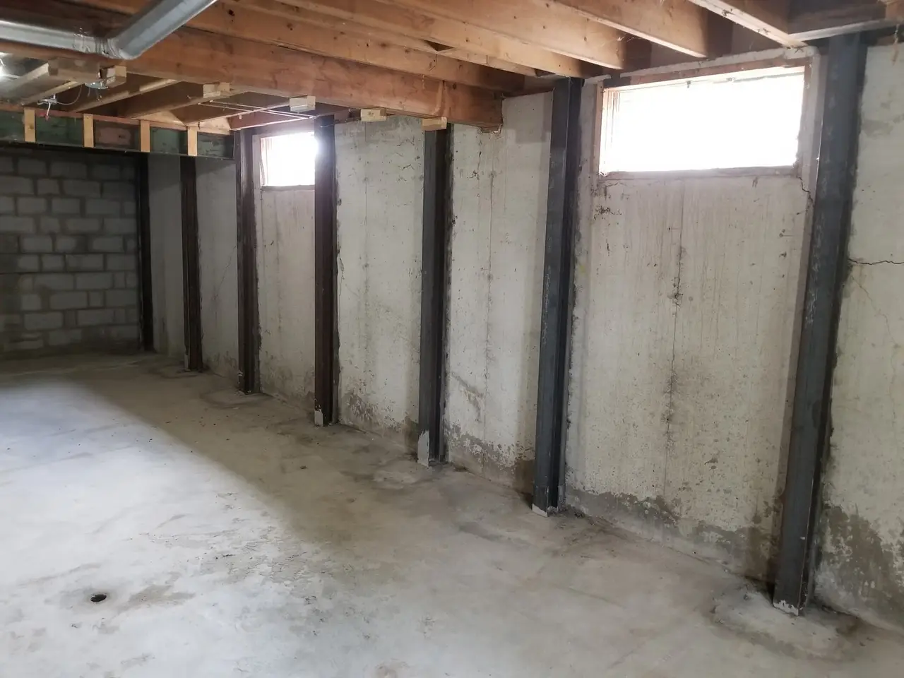 Steel wall braces installed along the foundation walls of an unfinished basement