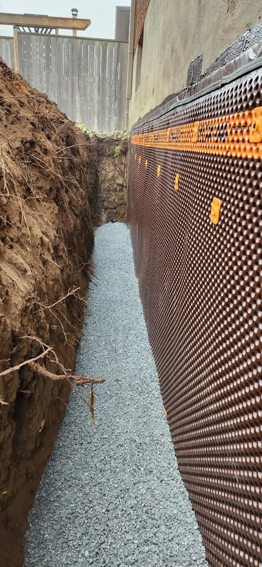 Dimpled drainage membrane and clear stone along an excavated foundation wall