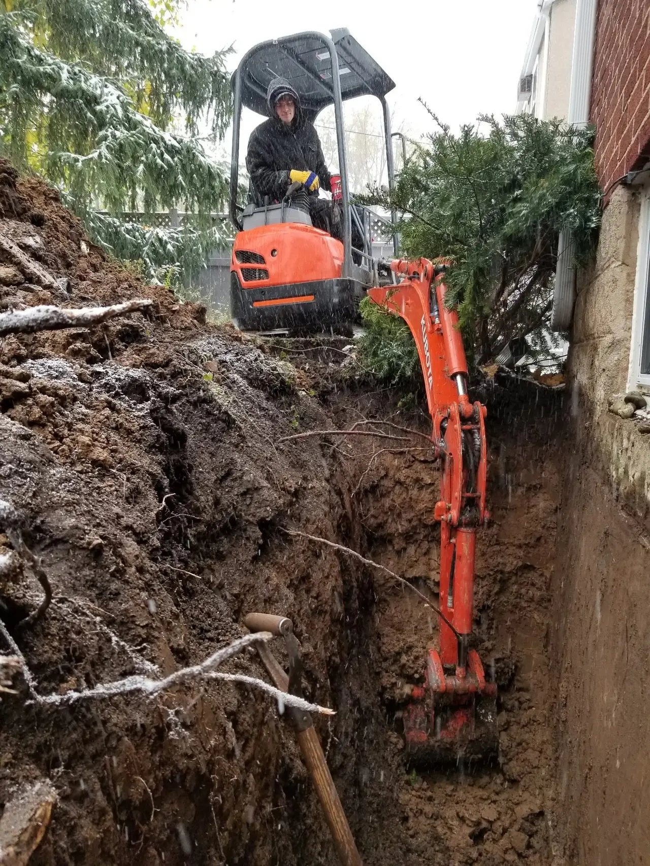 AVH mini excavator digging along a foundation wall for exterior work