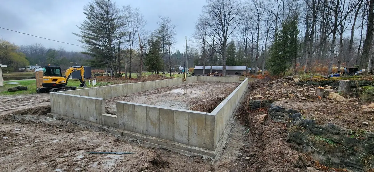 New concrete foundation for an addition, excavator on site, poured and stripped