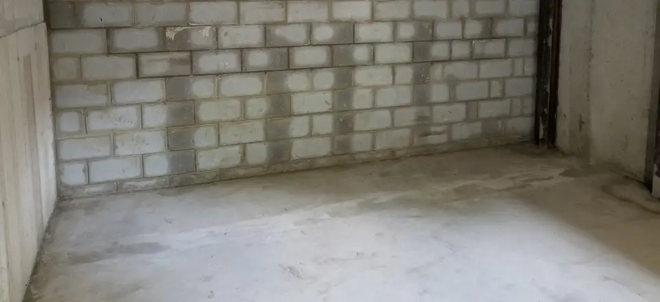 Basement with a new concrete floor slab poured against a clean block wall