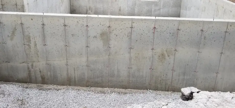 Freshly poured concrete foundation walls with form ties, ready for backfill