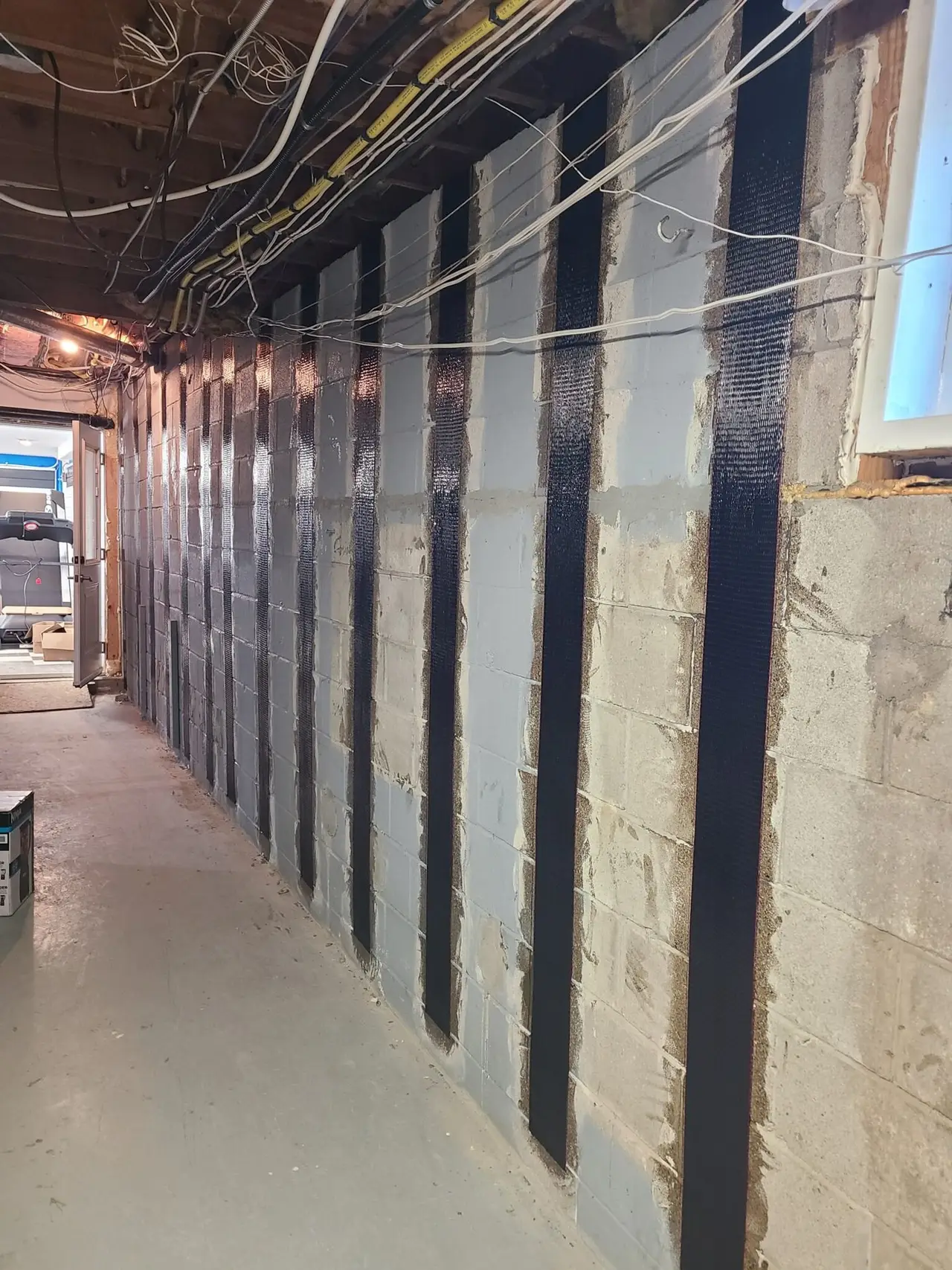 Carbon fibre reinforcement straps bonded to a basement foundation wall