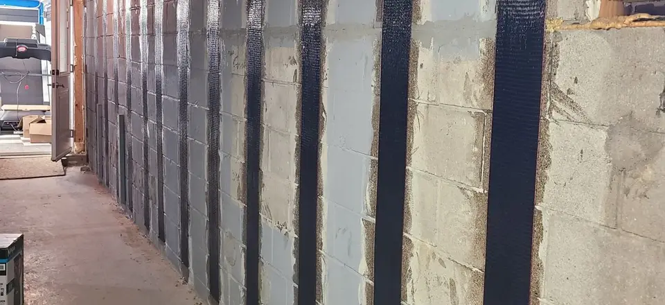 Carbon fibre reinforcement straps bonded to a basement foundation wall