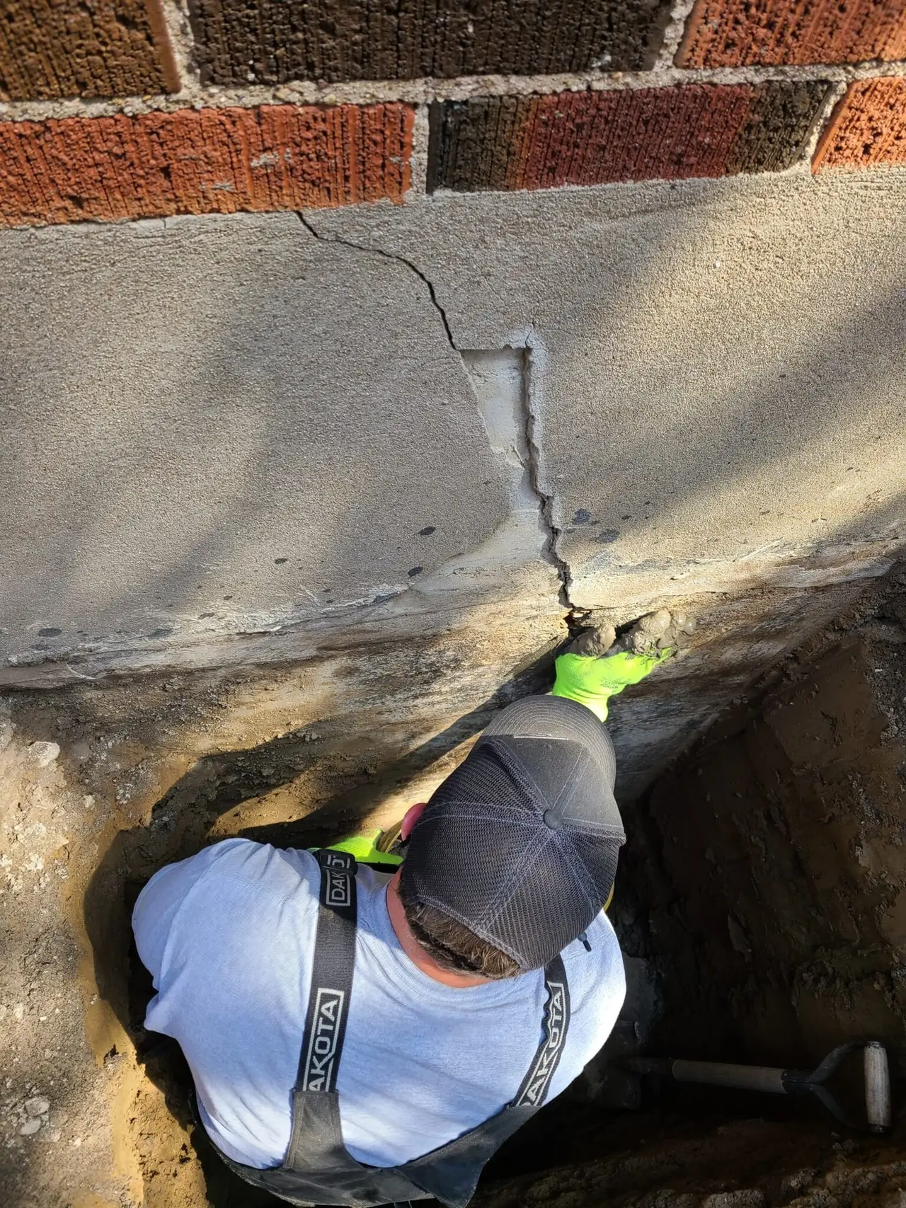 Basement Worx technician repairing a poured concrete foundation from the outside