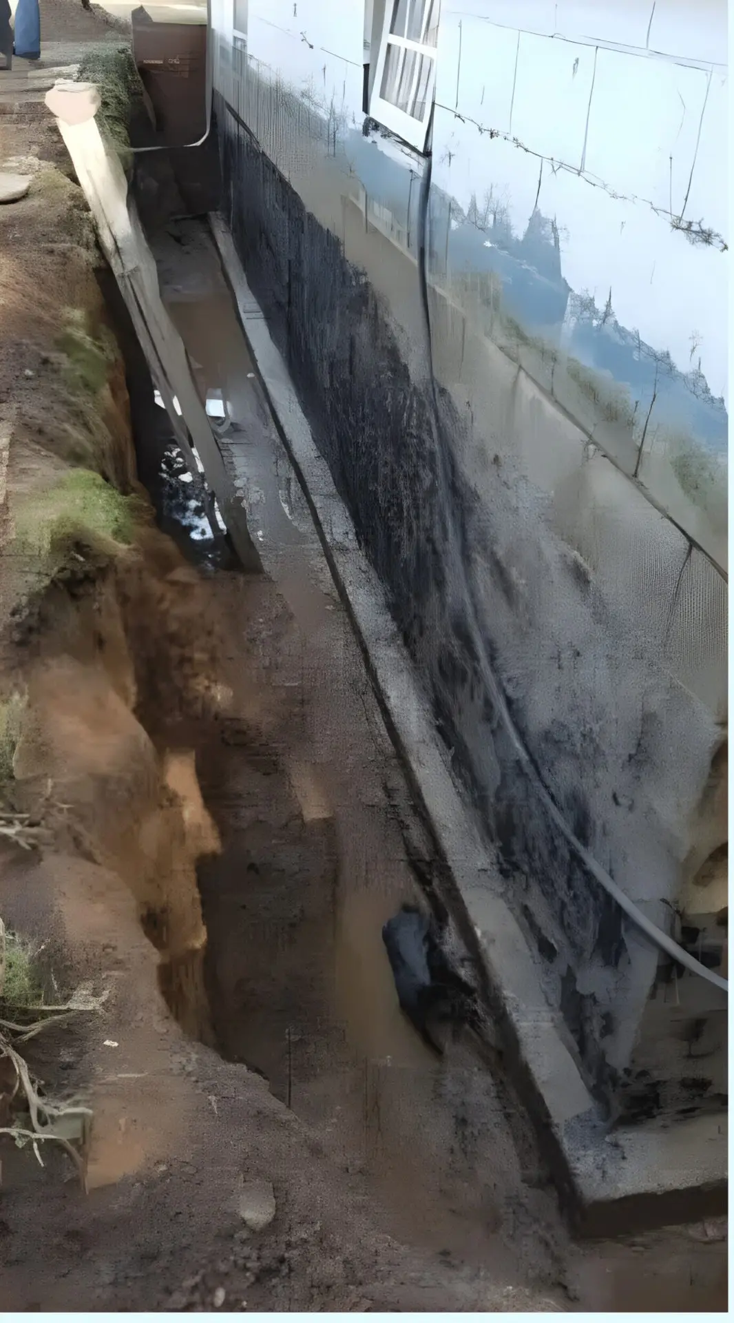 Excavated trench along a foundation wall with new waterproofing membrane