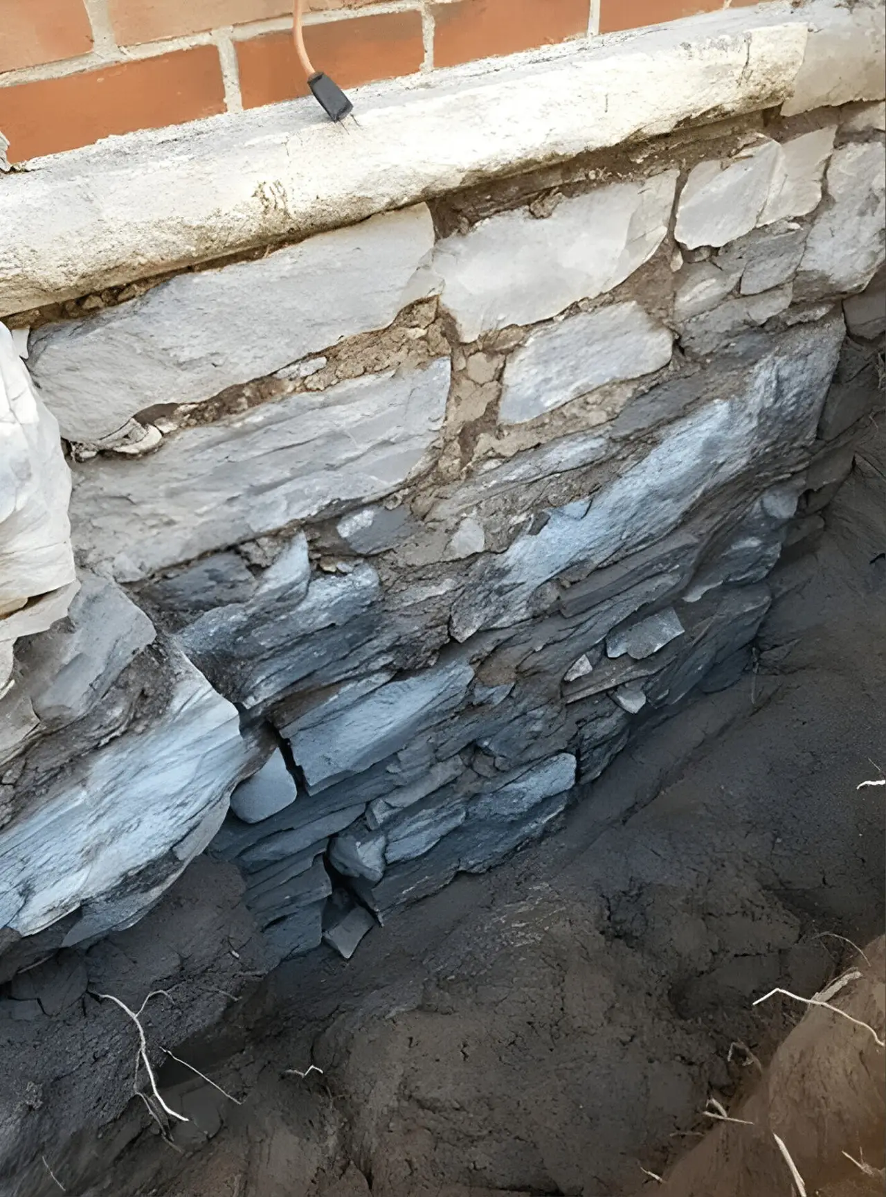 Century-home stone foundation wall exposed for repointing and parging